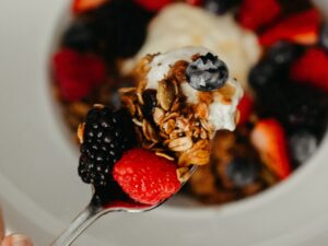 a close up of a spoon with granola and fresh fruit