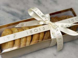 a box of cookies on a marble table, tied with an ai fiori ribbon