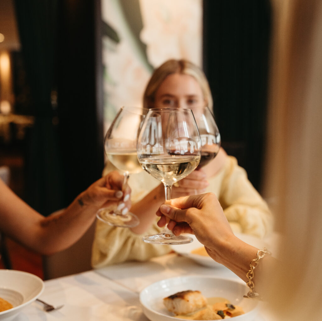 a group of people cheers-ing glasses of wine