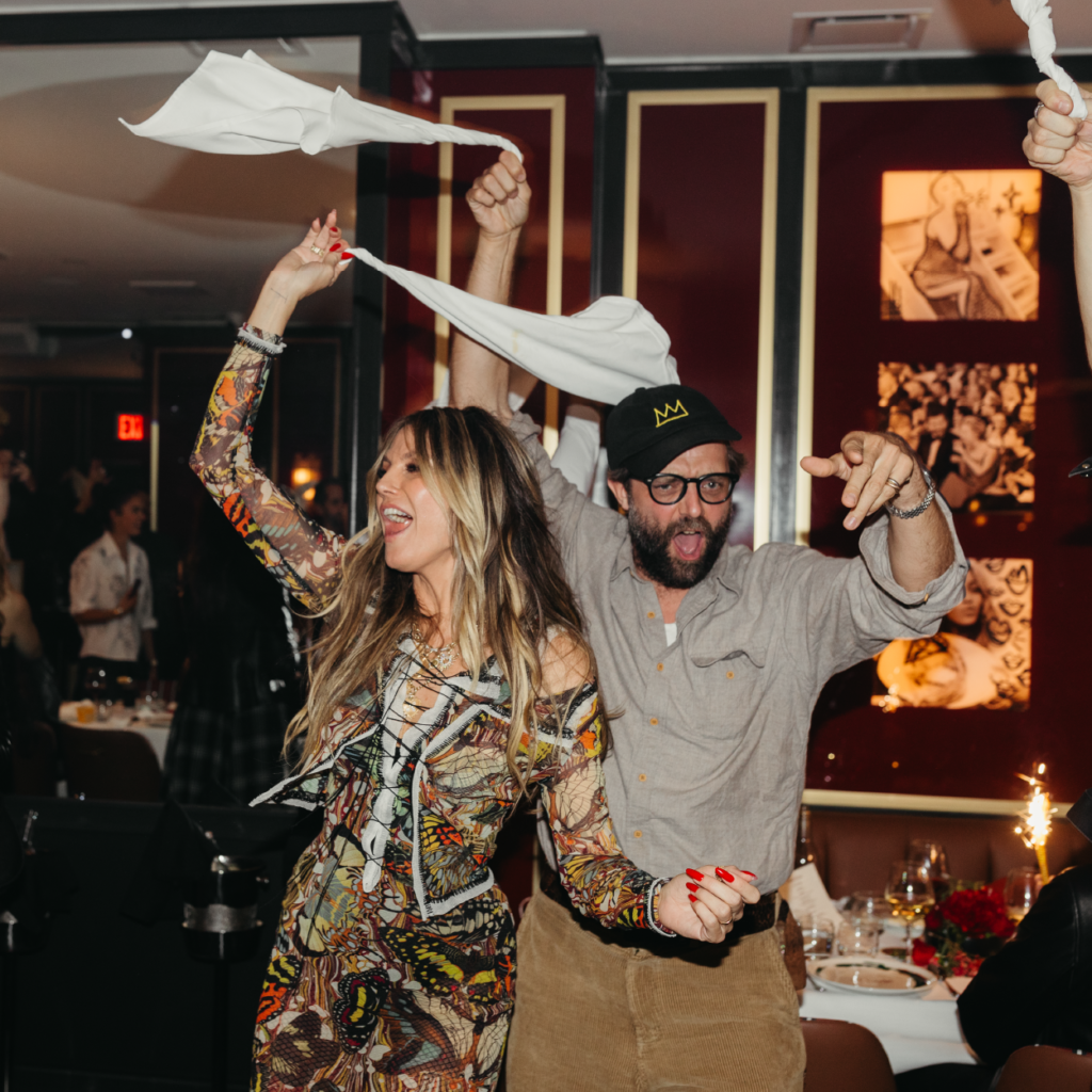 heidi klum and a male friend swinging a napkin above her head at crazy pizza