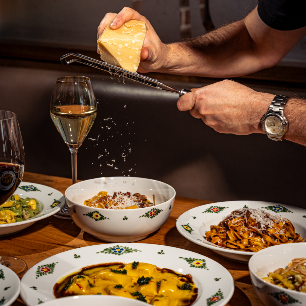 a chef grating a block of Parmesan cheese onto a bowl of pasta at osteria morini dc