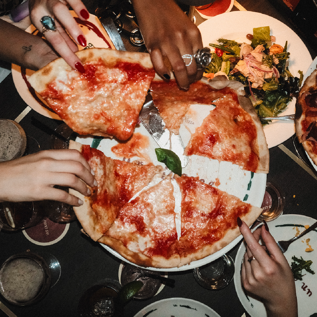 hands grab slices of pizza at crazy pizza