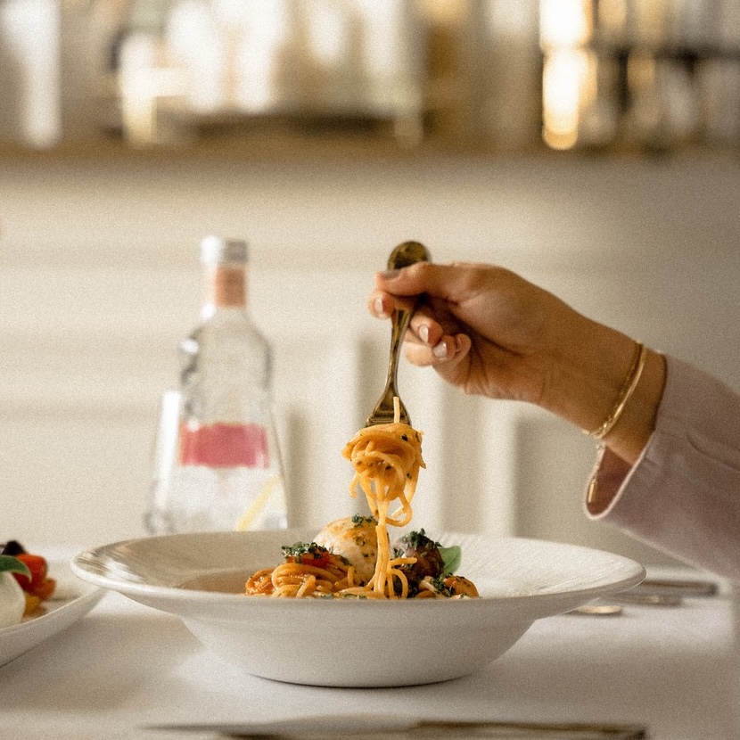 a hand twirling spaghetti in a bowl